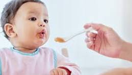Mother feeding 6-month-old baby solid food for the first time – starting solids journey with traditional Indian weaning food